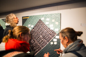 Mehrere Personen steven vor einer Luftaufnahme und markieren Positionen mit kleinen Zetteln.