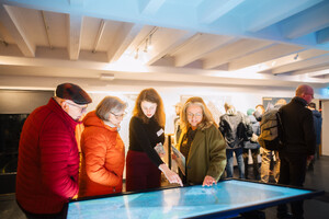 Vier Personen, darunter Senatorin Özlem Ünsal, stehen interessiert an einem interaktiven Stadtplan.